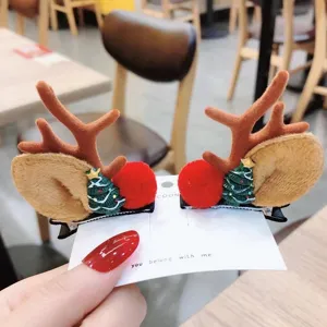 Primer plano detallado de pinzas para el cabello de reno navideño con pino y pompón rojo.