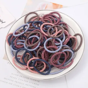 Detailed shot of multi-color elastic mini hair ties displayed in a white ceramic plate.