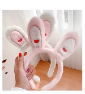 Dettaglio fascia per capelli con orecchie di coniglio di peluche, cerchietto rosa con ricamo cuore.