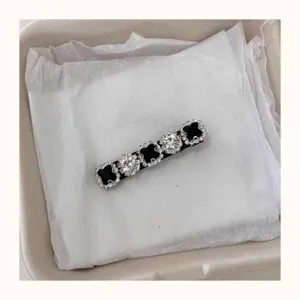 Rhinestone clover hair clip detail, elegant black side duckbill hair accessory for women.