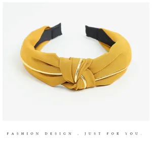 Close-up view of the stylish yellow fabric knotted headband with metallic gold piping.