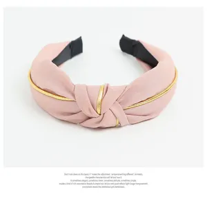 Close-up detail of the Korean style pink fabric knot headband with gold trim, wide design.