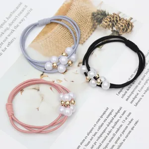 Detailed close-up shot of multi-strand pearl and gold bead hair ties in grey, black, and pink.