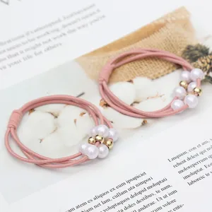 Detailed view of pink elastic hair tie adorned with faux pearls and gold beads for women styling.
