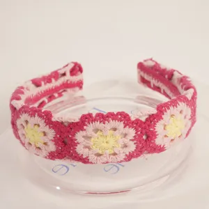 Crochet floral headband detail, pink and yellow knitted hair hoop close up showing texture.