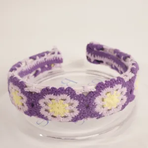 Detailed view of bohemian crochet headband, purple knit wide hair hoop with yellow floral motifs.