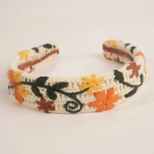 Gros plan détaillé du serre-tête en tricot brodé floral bohème, accessoire de vacances.