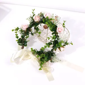 Close-up detail of pink rose floral hair wreath with green leaves and elegant white ribbon.
