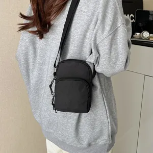 Close-up view of the black minimalist crossbody phone bag, showing front pocket and durable strap.