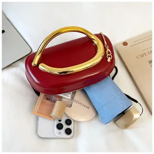 Detail shot of red oval handbag with gold metal handle and capacity display with daily items.