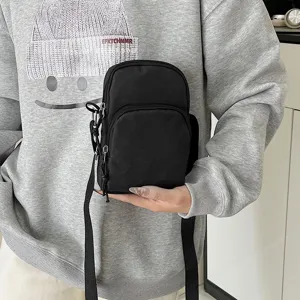 Close up detail of black nylon crossbody shoulder bag with zipper pockets and adjustable strap.