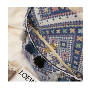 Detail view of ethnic woven tote bag featuring colorful tassels and metal magnetic snap.