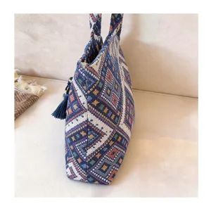 Close-up detail of the ethnic woven tote bag showcasing geometric patterns and tassel accessory.