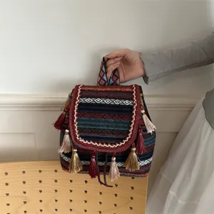 Ethnic woven backpack detail showcasing colorful geometric diamond print and tassel charms.