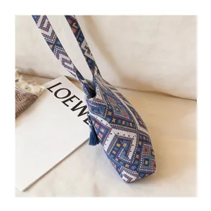 Detailed view of bohemian woven shoulder bag with ethnic geometric pattern and tassel.