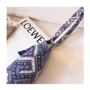 Detail view of a vintage ethnic woven tote bag with geometric patterns and blue tassel accent.