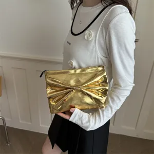 Shiny gold metallic clutch bag for women with elegant bow knot design and spacious interior.