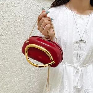 Red crossbody shoulder bag detail featuring a stylish gold ring handle and chic chain strap.