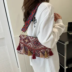 Detail shot of ethnic style woven crossbody bag with colorful strap and vintage tassels.