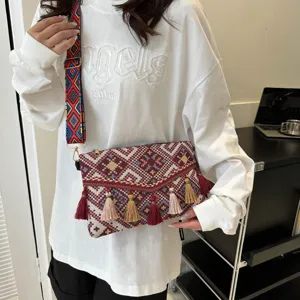 Detail view of ethnic woven crossbody bag with colorful tassels and geometric patterns.