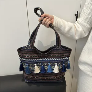 Ethnic style woven tote bag detail showcasing colorful fabric, tassels and double handles.