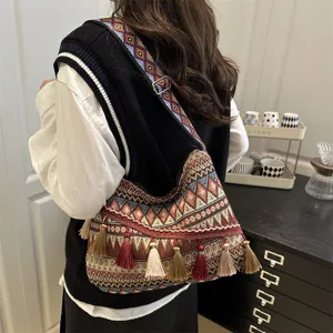 Detailed shot of ethnic geometric shoulder bag with colorful tassels, worn in a cozy room.