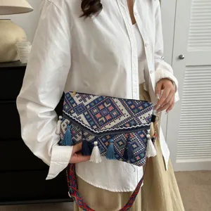 Detailed view of women's ethnic style woven envelope shoulder bag with colorful tassels.