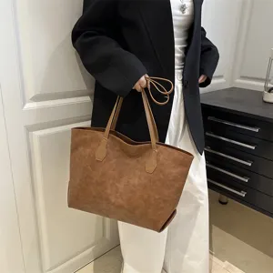 Detail shot of a stylish brown PU tote bag worn by a model in an indoor professional setting.