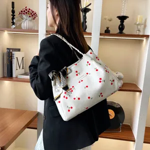 Vista dettagliata della borsa tote bianca in velluto a coste con stampa di ciliegie e foulard.