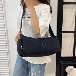Detailed shot of casual black shoulder duffel bag worn by model, showing style and capacity.