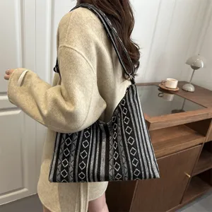 Detailed view of the black and white ethnic woven shoulder bag in a modern indoor scene.