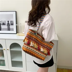 Detailed view of bohemian woven shoulder bag with colorful braided strap and decorative tassels.