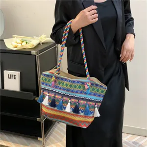 Detailed view of colorful ethnic woven tote bag with braided handles and stylish blue white tassels.