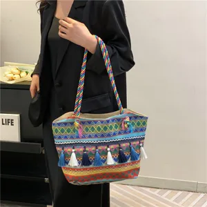 Detailed view of ethnic woven tote bag with colorful braided handles and tassels.