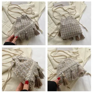 Woven tassel bucket bag with drawstring closure, stylish ethnic shoulder crossbody bag.