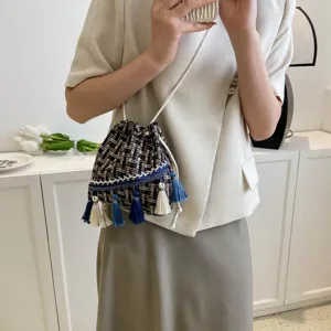 Detailed view of the ethnic style tweed bucket bag with blue and white tassels and drawstrings.