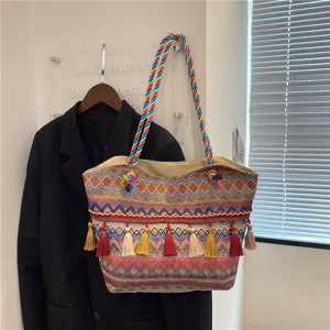Detailed view of bohemian woven tote bag with colorful braided handles and tassels.