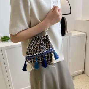 Ethnic style tweed woven bucket bag detail view with blue white tassels and drawstring.