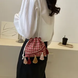 Ethnic style red tweed bucket bag with colorful tassels and crossbody strap detail.