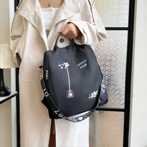 Women's multi-functional black backpack with floral embroidery and top handle design.