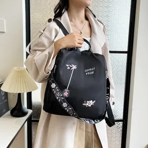 Detailed shot of casual black nylon backpack with exquisite flower embroidery and strap.