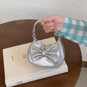 Detailed view of children's silver metallic bow handbag, elegant mini purse close up shot.