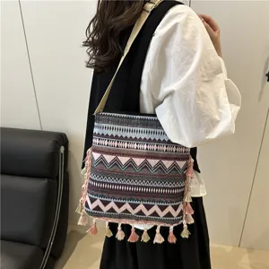 Detailed view of ethnic bohemian shoulder bag featuring woven geometric patterns and fringe tassels.