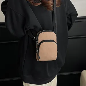 Detail view of the mini crossbody phone bag with dual zipper compartments and durable strap.