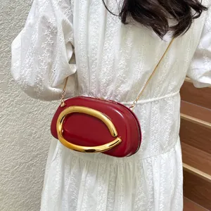 Detail view of red mini shoulder bag with gold metal handle and chain strap, elegant style.