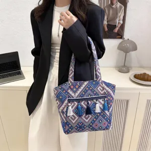 Ethnic style tote bag detailed shot showing intricate blue patterned fabric and delicate tassels.