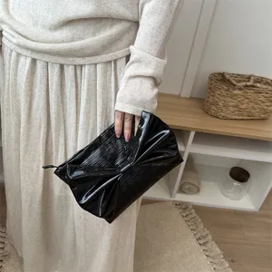 Black patent leather bow clutch bag, elegant evening purse with chic bow detail for women.