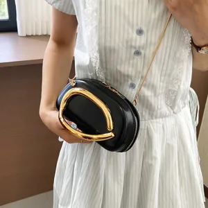 Mini black crossbody bag with luxury gold metal handle and chain strap for modern women daily.
