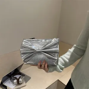 Silver metallic evening clutch bag for women featuring a large bow detail and stylish design.