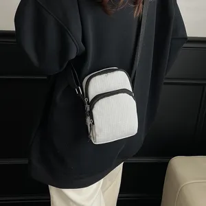 Detail shot of casual crossbody bag worn by model, showing grid fabric and zipper.